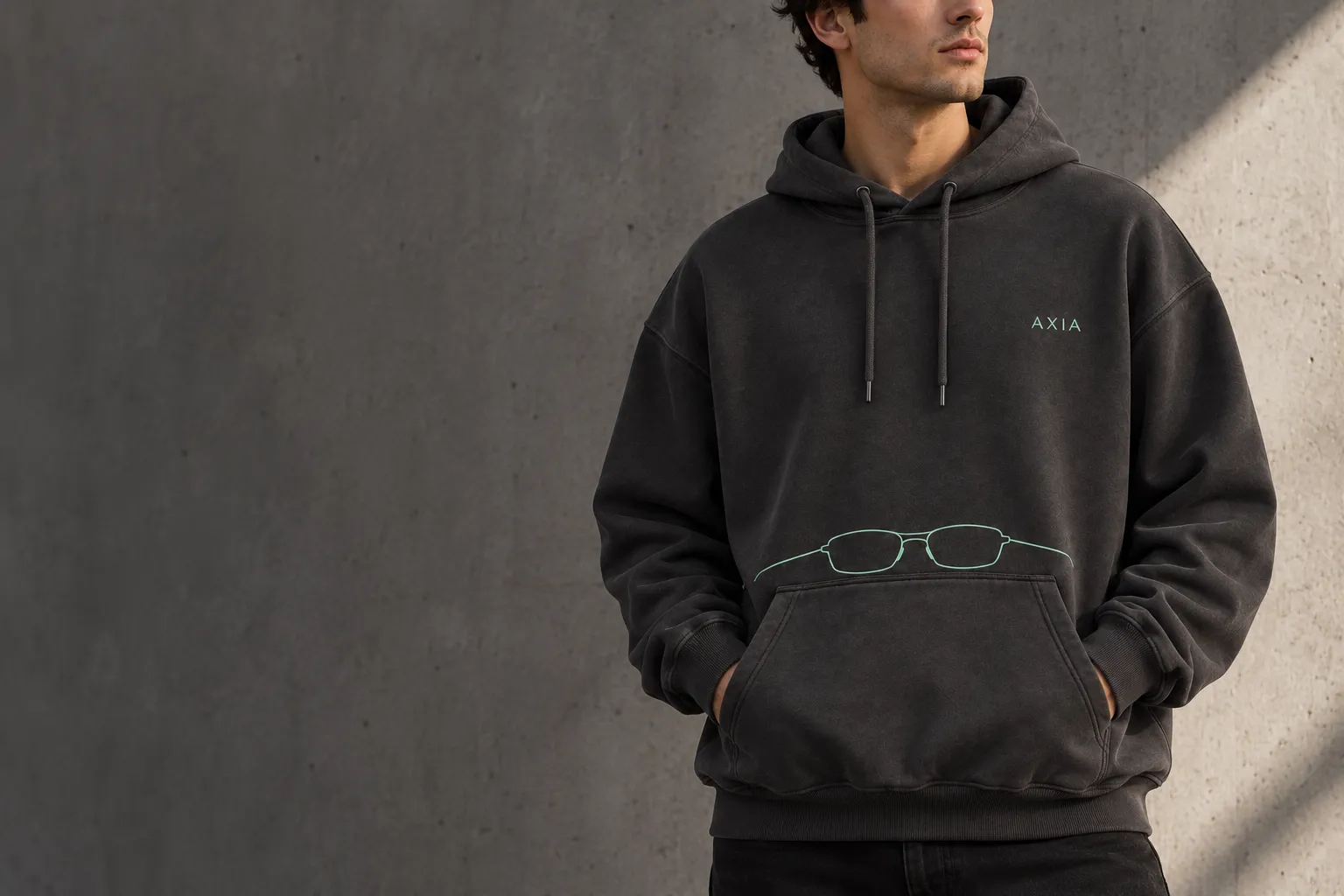 Visualización conceptual de Frame Hoodie AXIA carbón con firma y gráfico de gafas en menta, sobre un modelo.
